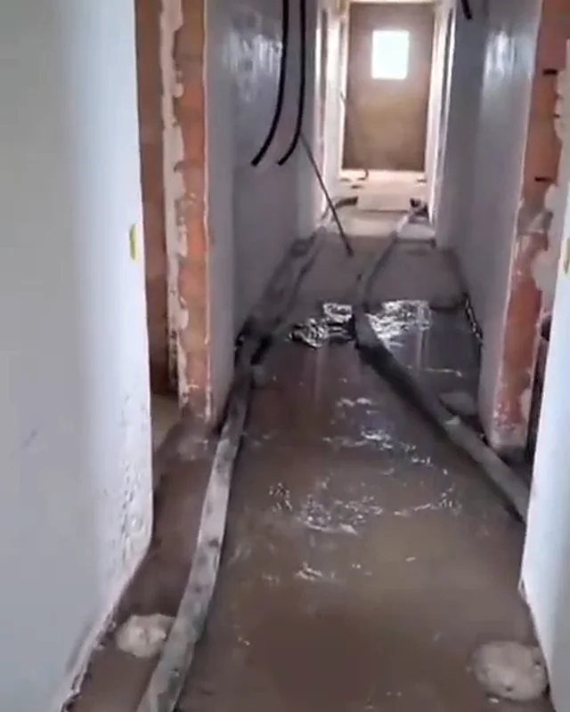 Mangueira levando a massa pelo corredor de um andar em obra